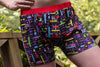 Man posing with hand on hip, wearing 8-Bit Baby Boxer Briefs. Red Waistband, Black Background and multicolor pattern. 