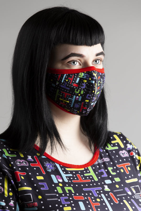 Model wearing 8-Bit Baby Face Mask and Onesie. Matching red trim, black background, and video game iconography. 